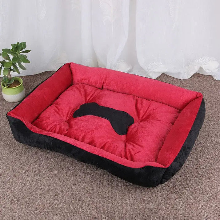 Red and black plush dog bed with bone-shaped cutout.