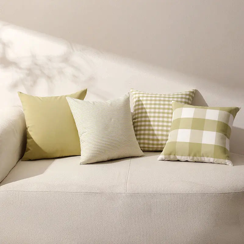 Four grass green sofa cushions with green-toned decorative pillows on a grass green sofa