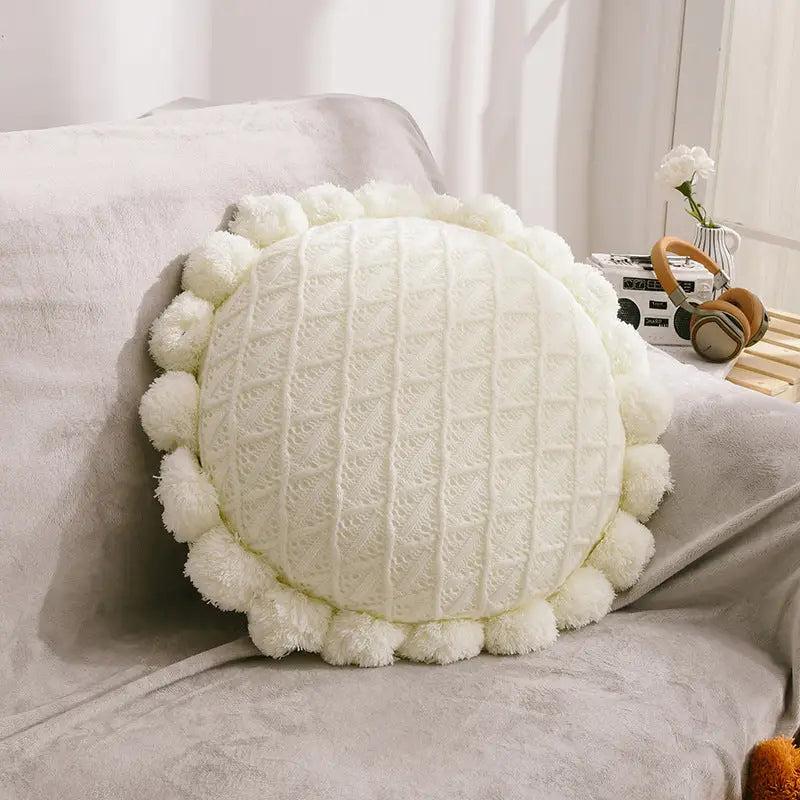Round, textured, pom-pom-edged pillow.