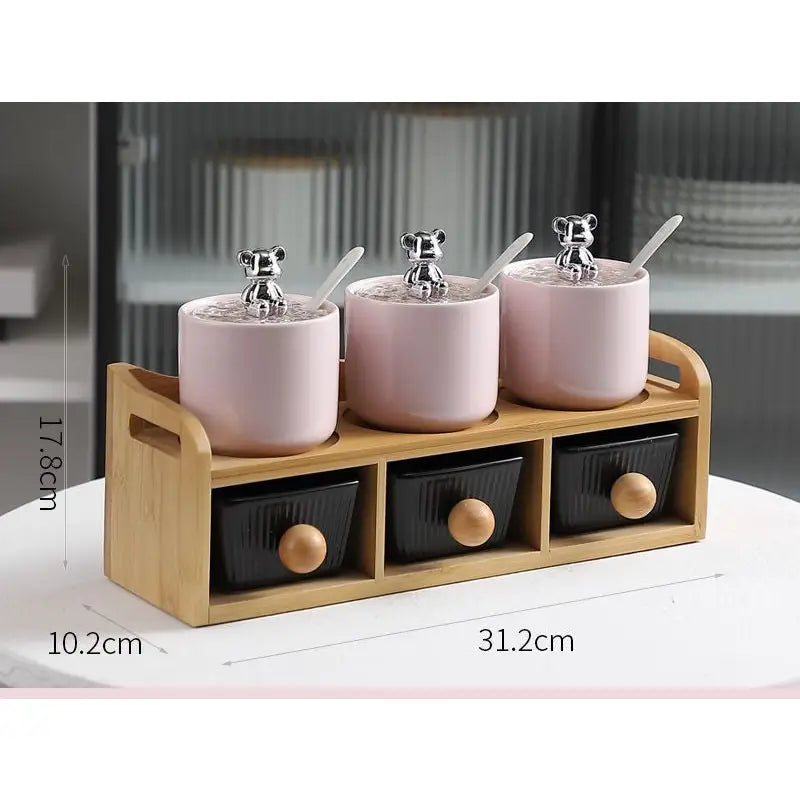 Pink ceramic spice jars with bear-shaped lids and wooden stand.