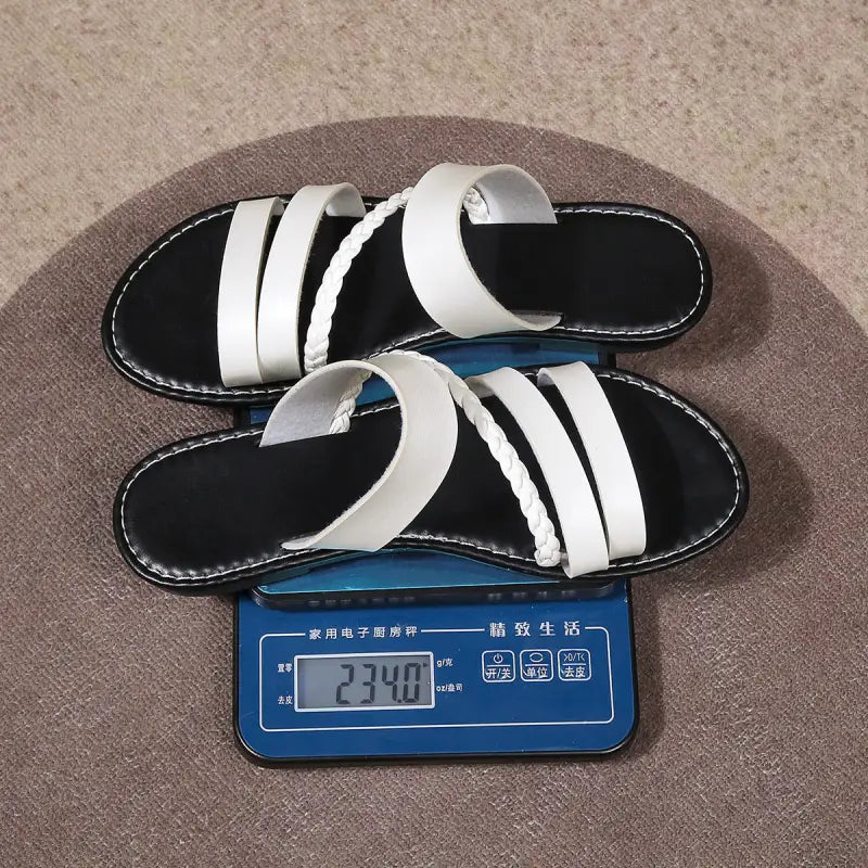 Pair of black and white sandals on a scale.