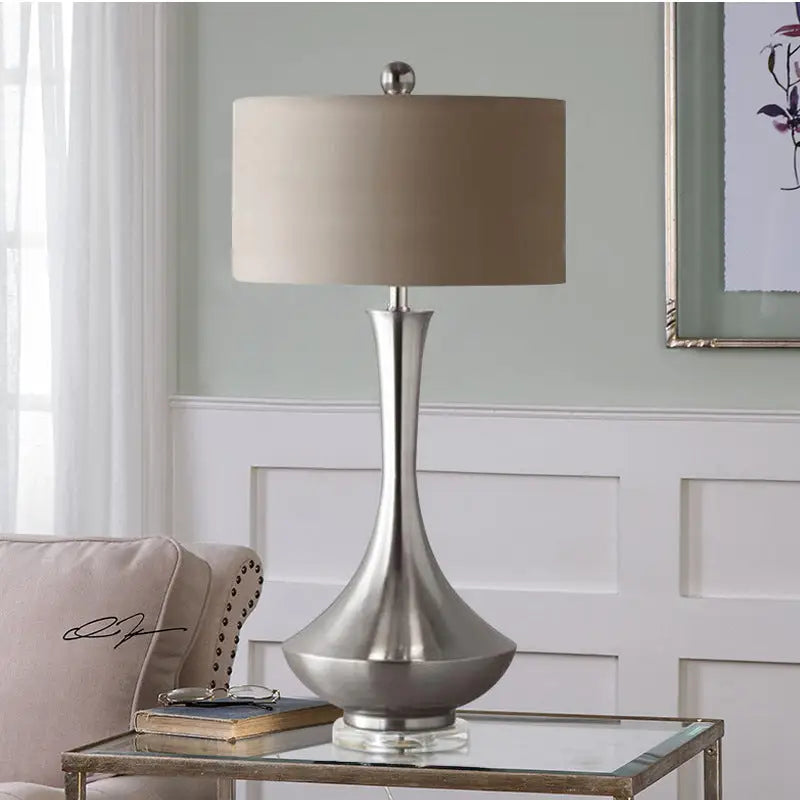 Brushed silver lamp with tan shade.