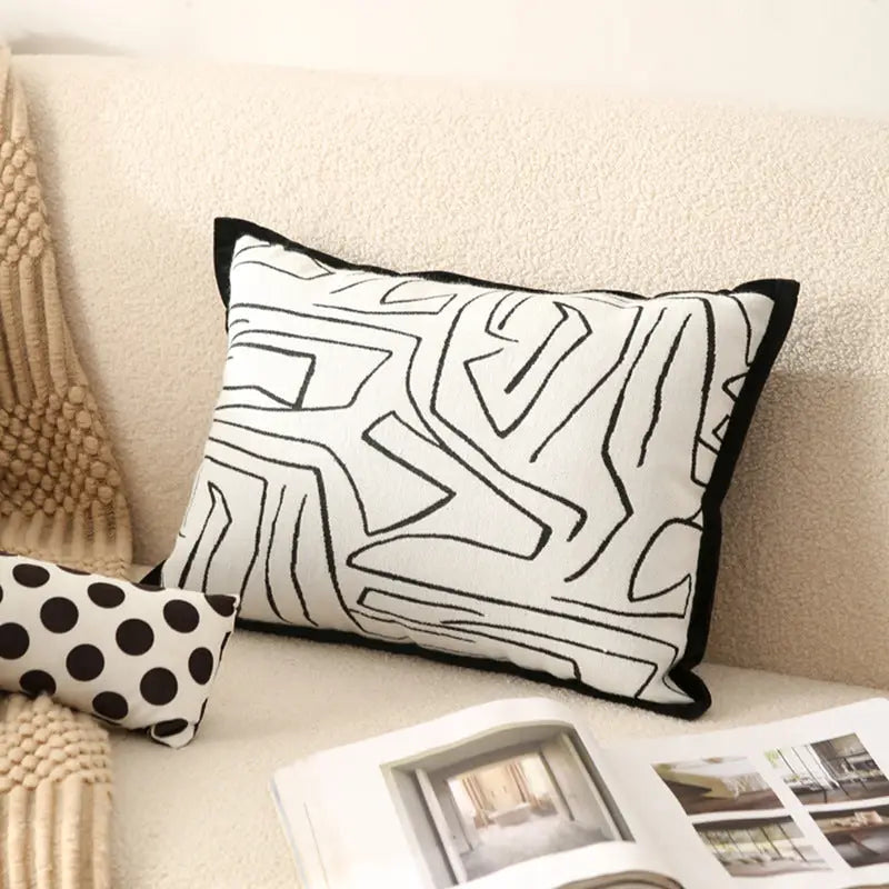 Rectangular pillow with black geometric pattern and trim.