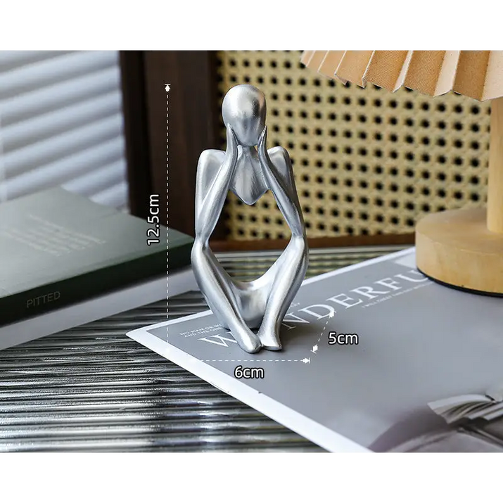 Silver-colored seated figure with hands on face.