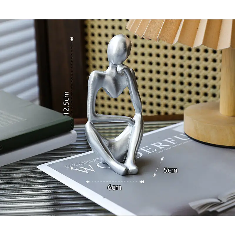 Silver-colored seated figure sculpture.