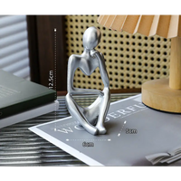 Silver-colored seated figure sculpture.