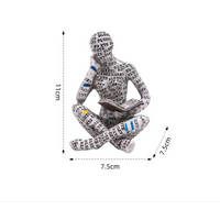 Figurine of a seated reader covered in text.