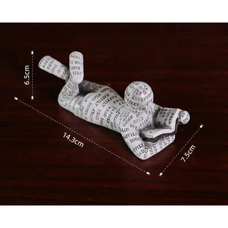 Figurine of a person reading a book, covered in text.