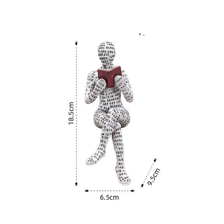 Figurine of a seated person covered in text, reading a book.