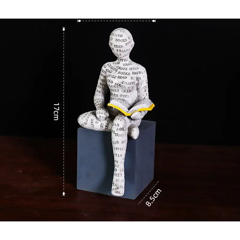 Figurine of a person reading a book, covered in words, sitting on a cube.