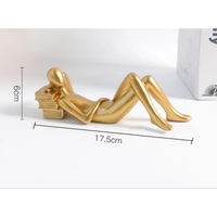 Golden reclining figure resting on books.