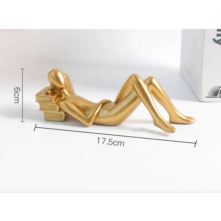Golden reclining figure resting on books.