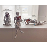 Three reading figure sculptures.