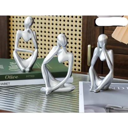 Three silver abstract thinker statues.