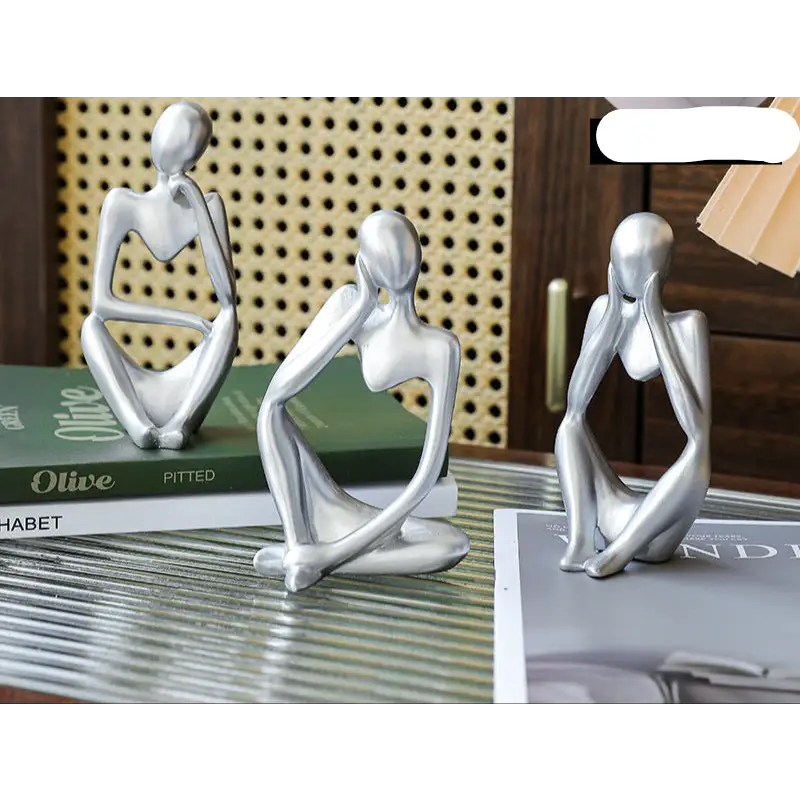 Three silver abstract thinker statues.