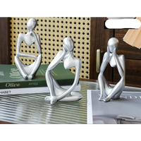 Three silver abstract thinker statues.