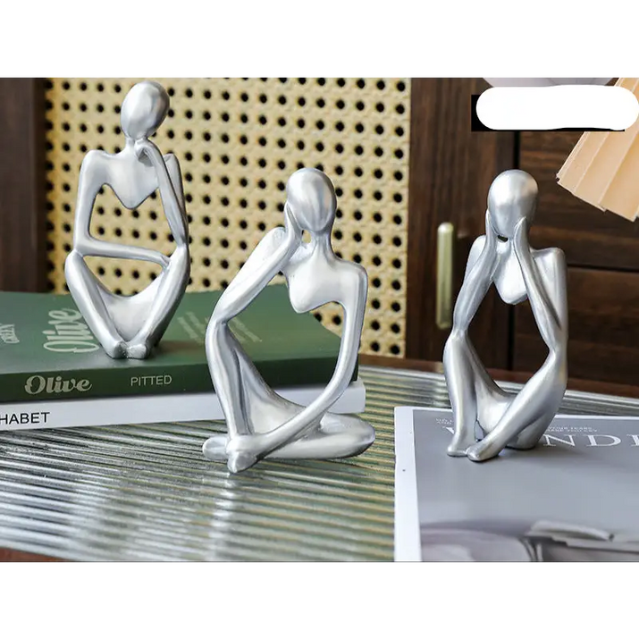 Three silver abstract thinker statues.
