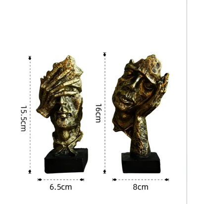 Two bronze-colored abstract face sculptures.