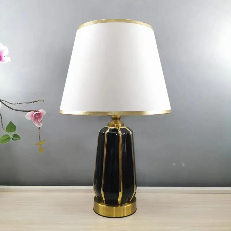 Black and gold ceramic lamp with white shade.