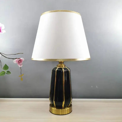 Black and gold ceramic lamp with white shade.