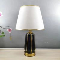 Black and gold ceramic lamp with white shade.