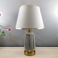 Gray and gold ceramic table lamp with white lampshade.