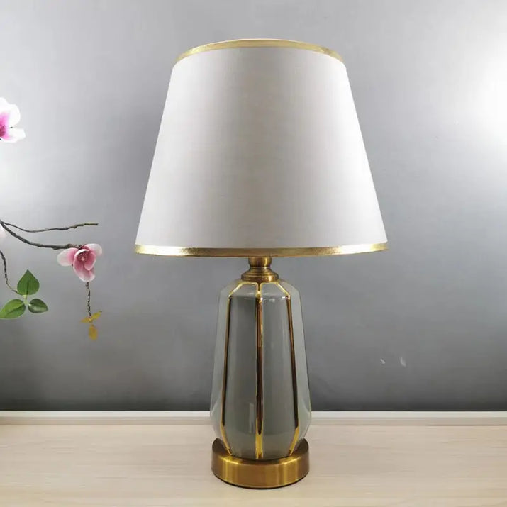Gray and gold table lamp with white shade.