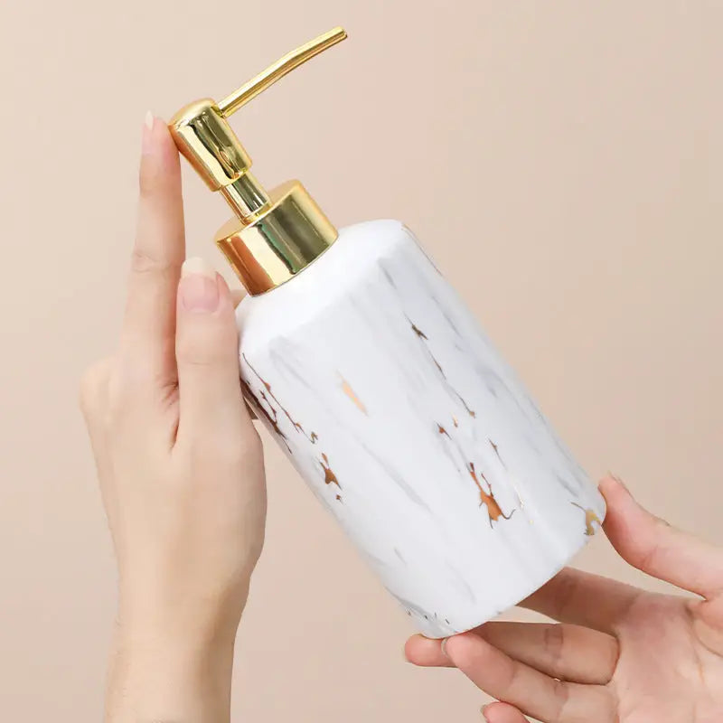 Marble-patterned soap dispenser with gold pump.