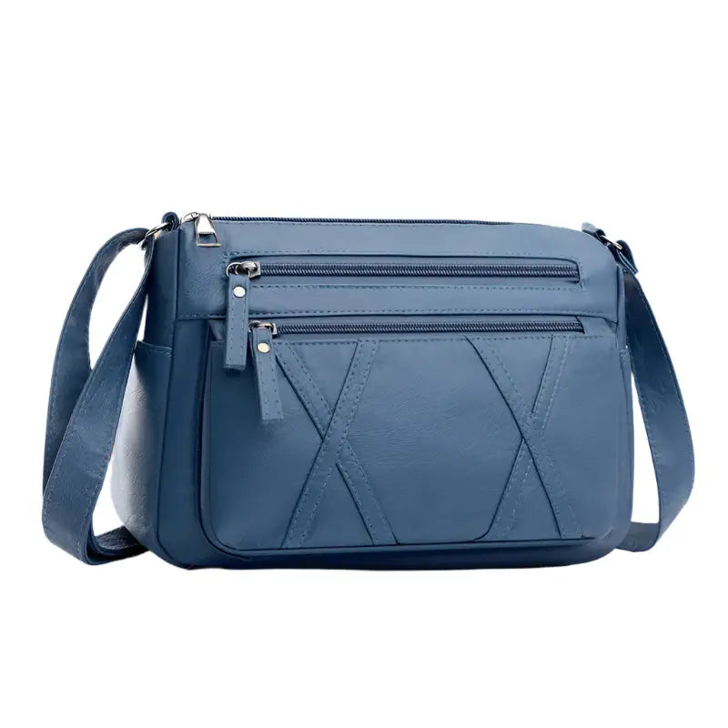 Blue crossbody bag with multiple zippered compartments.