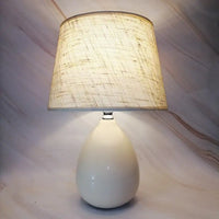 Illuminated white lamp with textured shade.