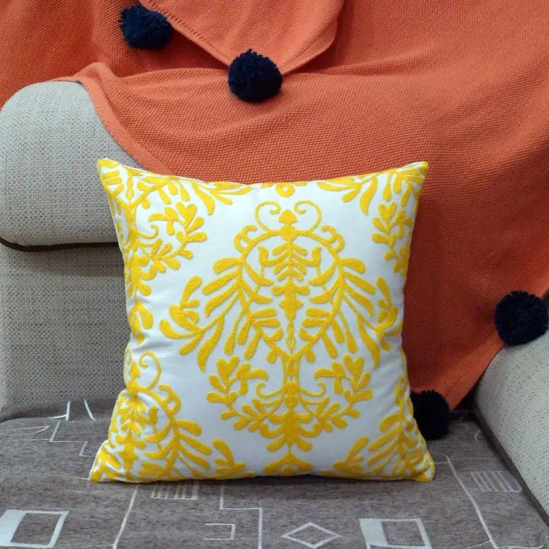 White pillow with yellow floral embroidery.