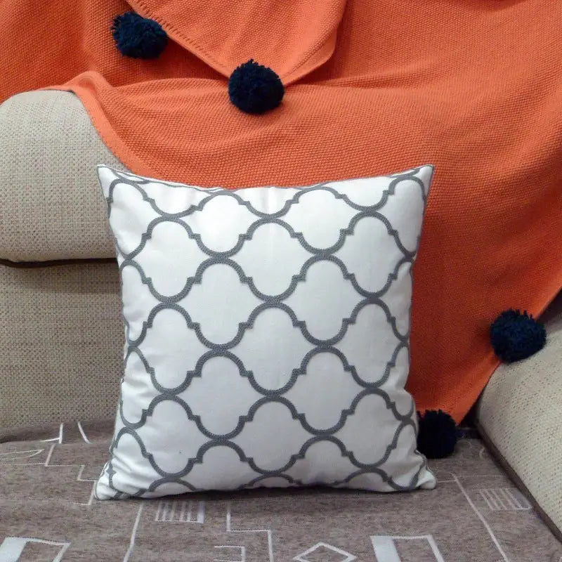 White pillow with gray quatrefoil pattern.
