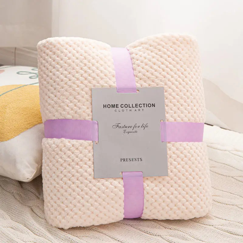 Folded cream-colored waffle blanket with lavender ribbon.