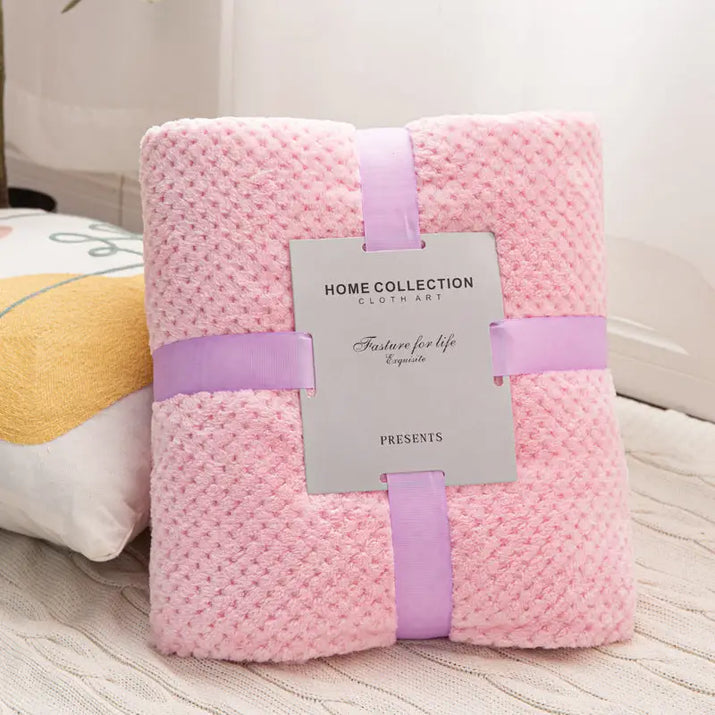 Pink textured blanket with ribbon and tag.