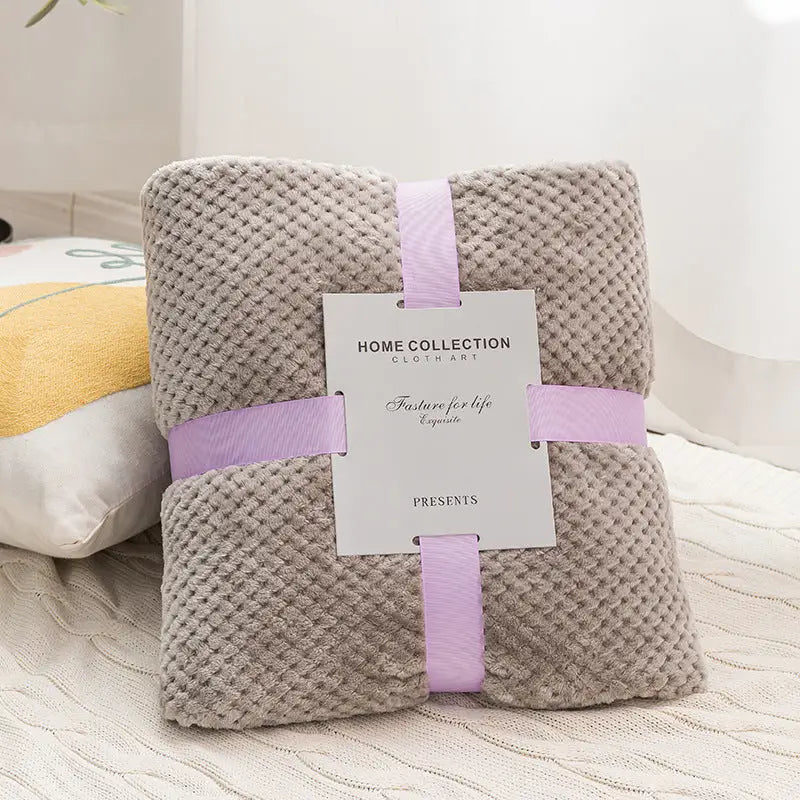 Folded gray plush blanket with ribbon and tag.