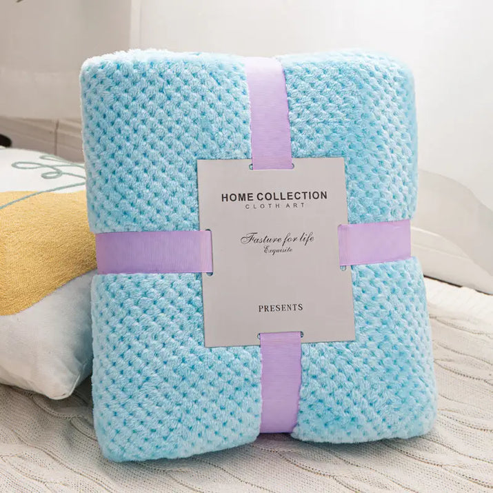 Folded, light blue, textured blanket with lavender ribbon.