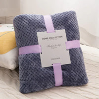 Folded gray plush blanket with ribbon and tag.