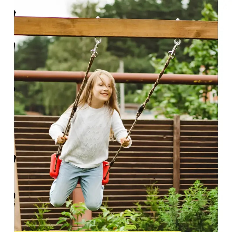 Girl on a red plastic outdoor kids curved swing in the yard