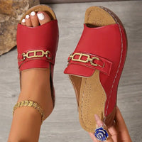 Red leather slide sandals with gold chain and metal buckle accents in platform design