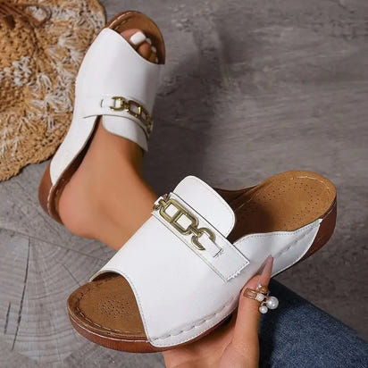 White leather open-toe sandals with gold chain and metal buckle accents, playfully stylish platform design