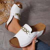 White leather open-toe sandals with gold chain and metal buckle accents, playfully stylish platform design