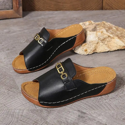 Black leather open-toe mules with gold chain detail and metal buckle accents for playfully stylish sandals