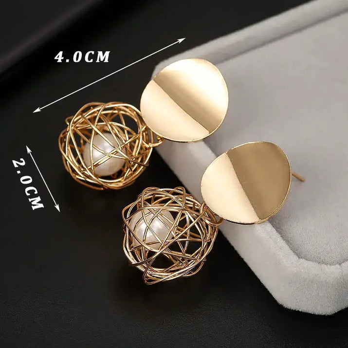 Gold-toned long drop earrings with pearl-center wire spheres showcasing retro charm