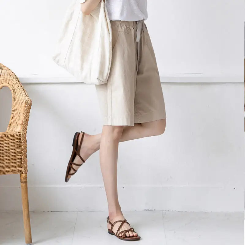 Woman wearing beige shorts and brown sandals.