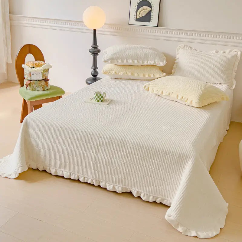 Ruffled white bedspread with matching pillows.