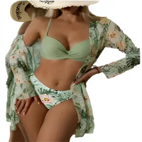 Woman in a green bikini with a floral cover-up and sun hat.