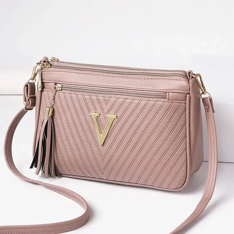 Mauve crossbody bag with gold V emblem, versatile shoulder women’s purse