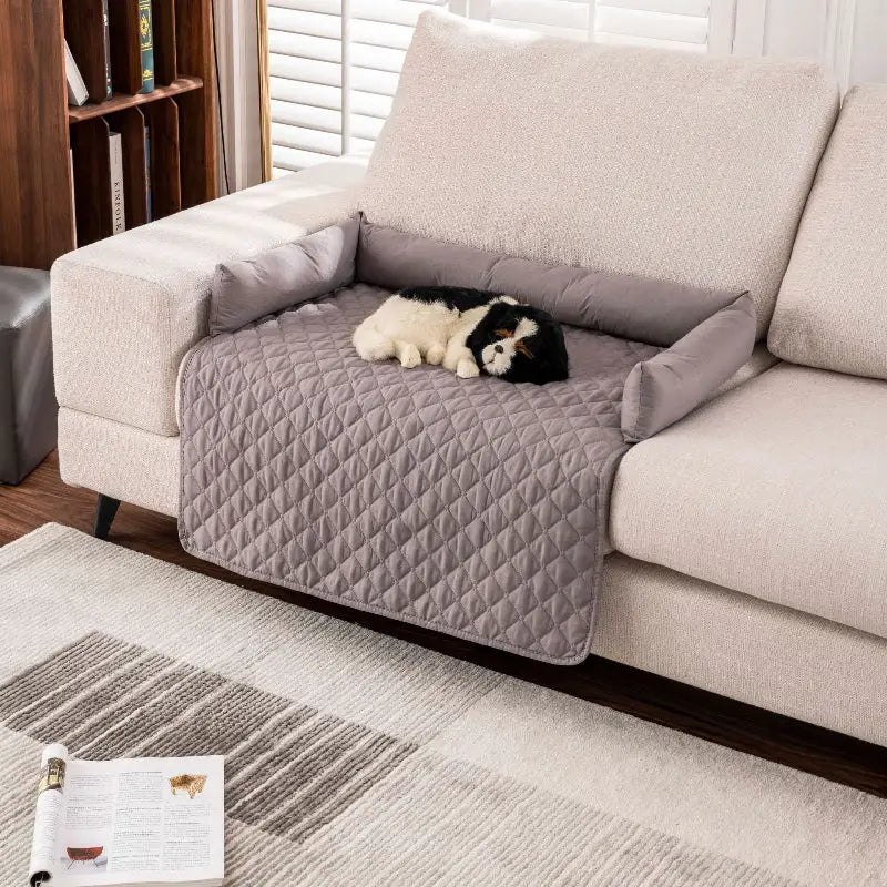 Quilted gray sofa protector with bolster arms on waterproof pet mat for dogs and cats